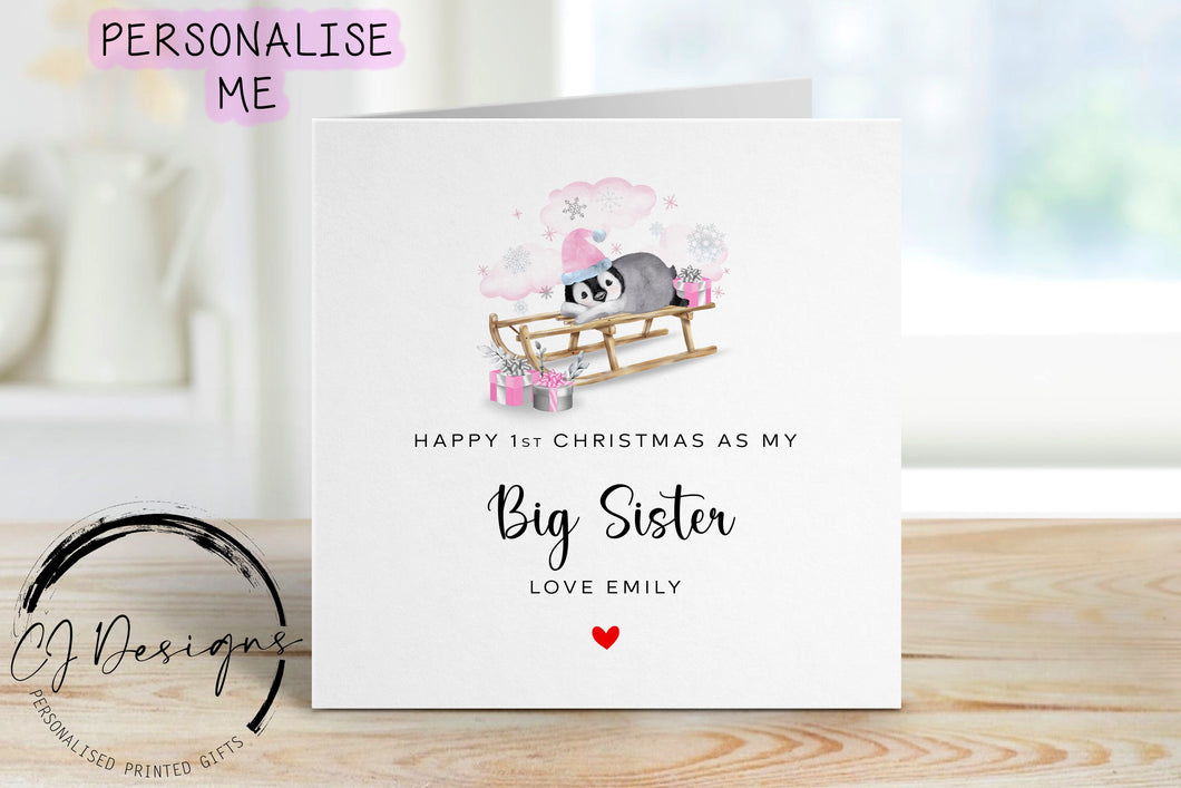 Little Girl First Christmas as my Big Sister personalised christmas card in a pink theme with picture of baby penguin wearing a pink christmas hat on a sledge