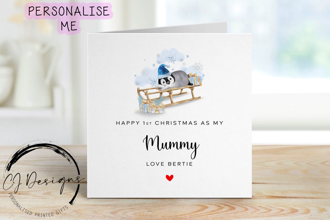 Little Boy First Christmas as my Mummy personalised christmas card in a blue theme with picture of baby penguin wearing a blue christmas hat on a sledge