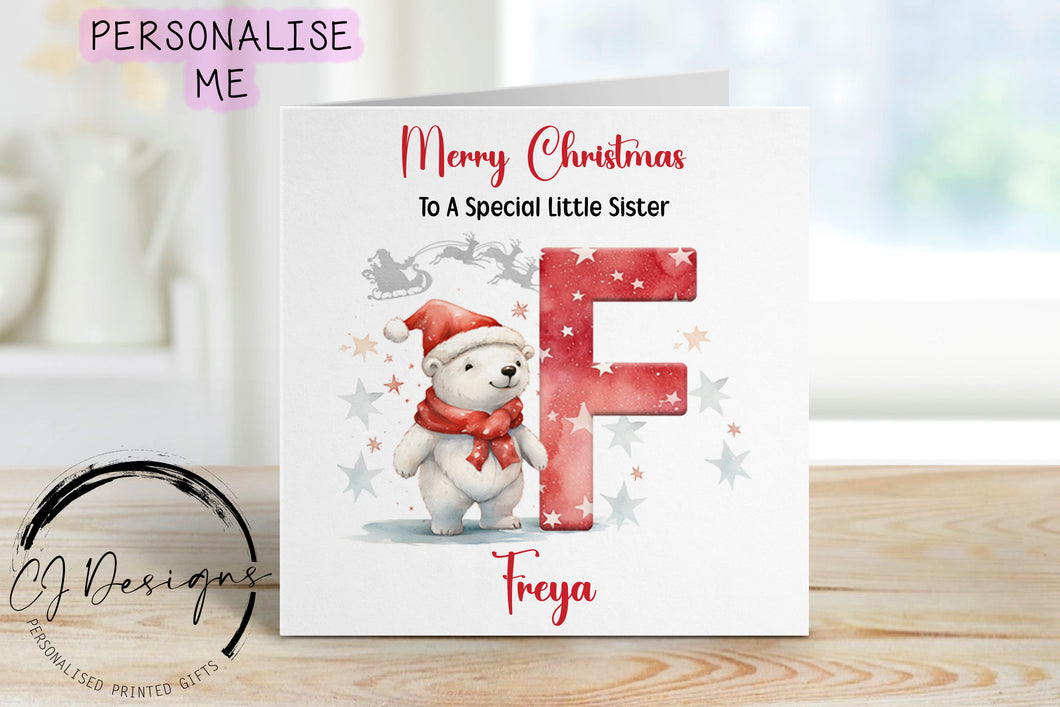 Little Sister personalised Christmas card with a polarbear wearing a christmas hat stood next to a large red letter which depicts the first letter of your little