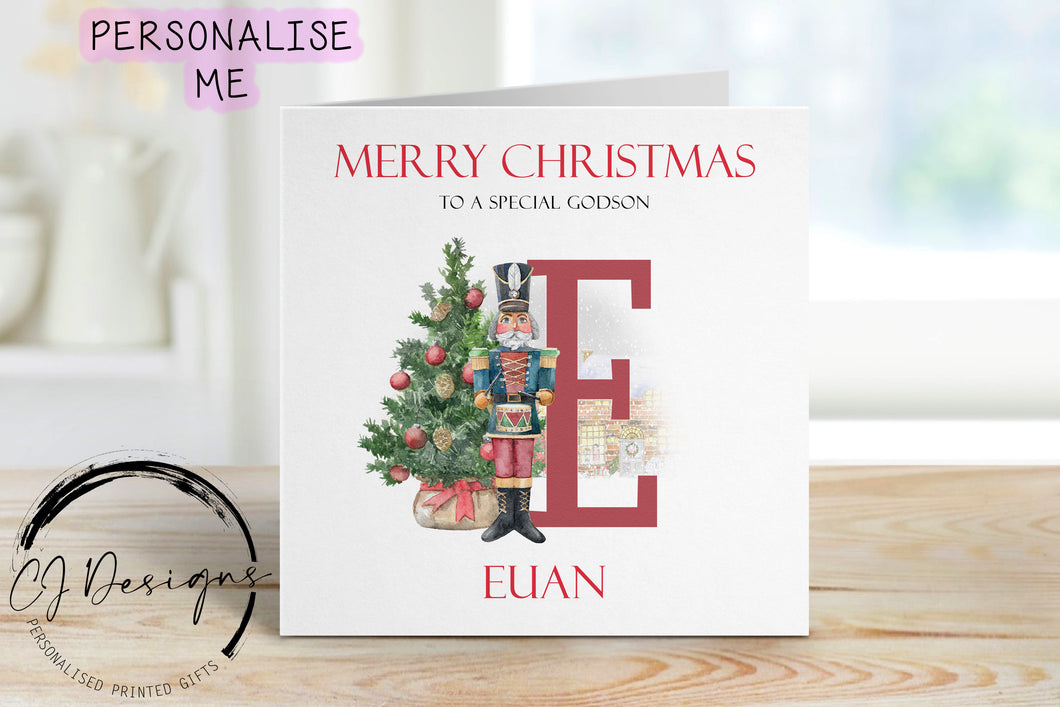 Godson personalised Christmas card with a nutcracker with Christmas Tree sstood next to a large red letter which depicts the first letter of your little